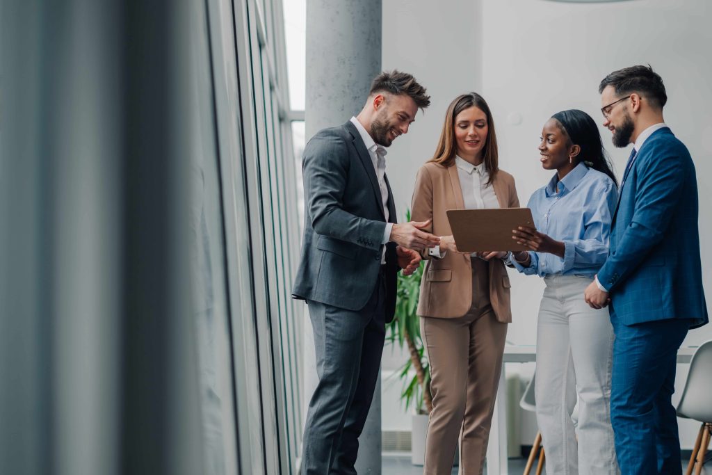 Eine Gruppe von Analysten bespricht in einem modernen Büro ein Klemmbrett mit Finanzdaten. Sie diskutieren über langfristige Krypto-Prognosen und das Potenzial von Bitcoin.